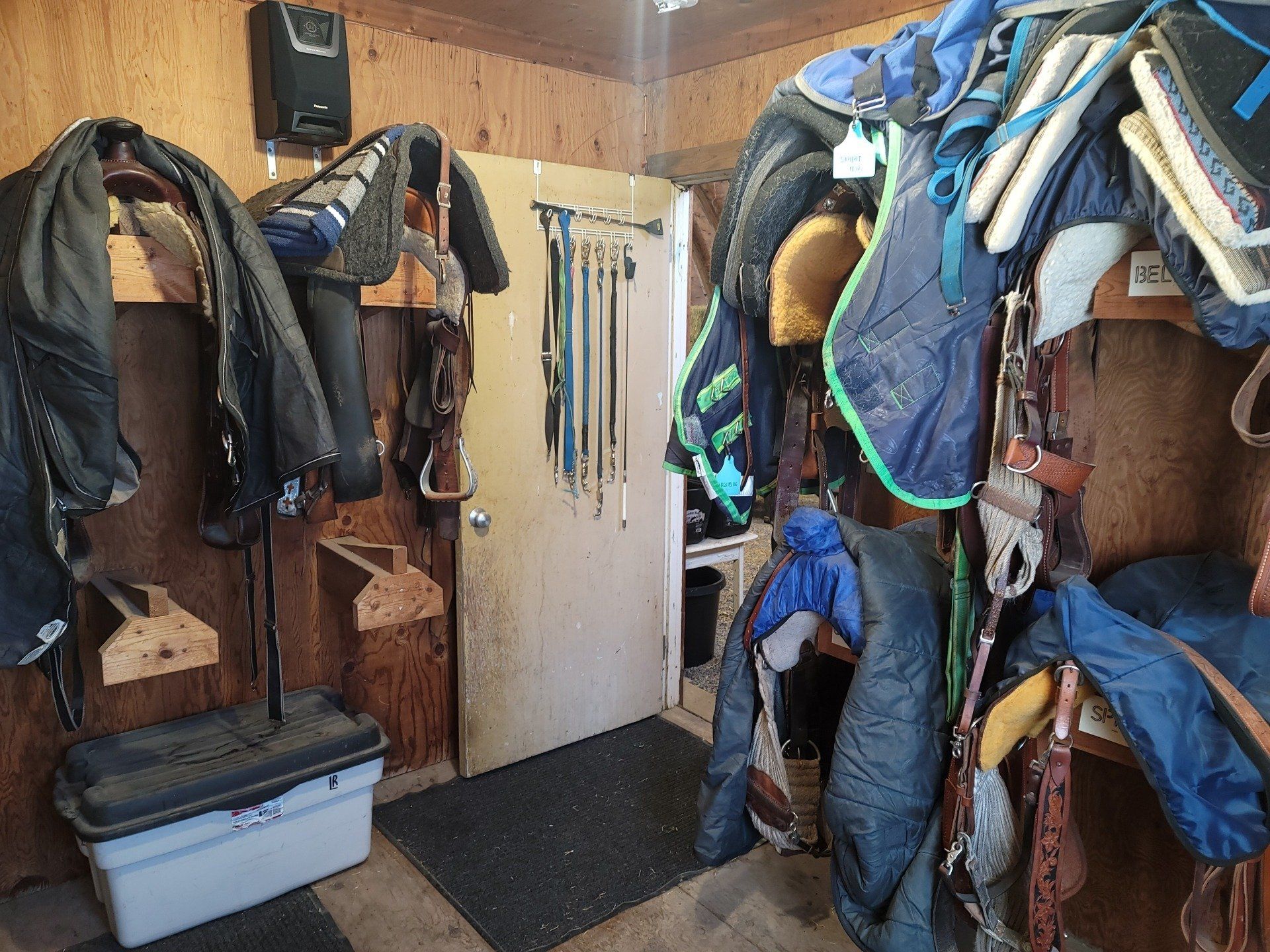 A stable with a lot of saddle pads hanging on the wall.