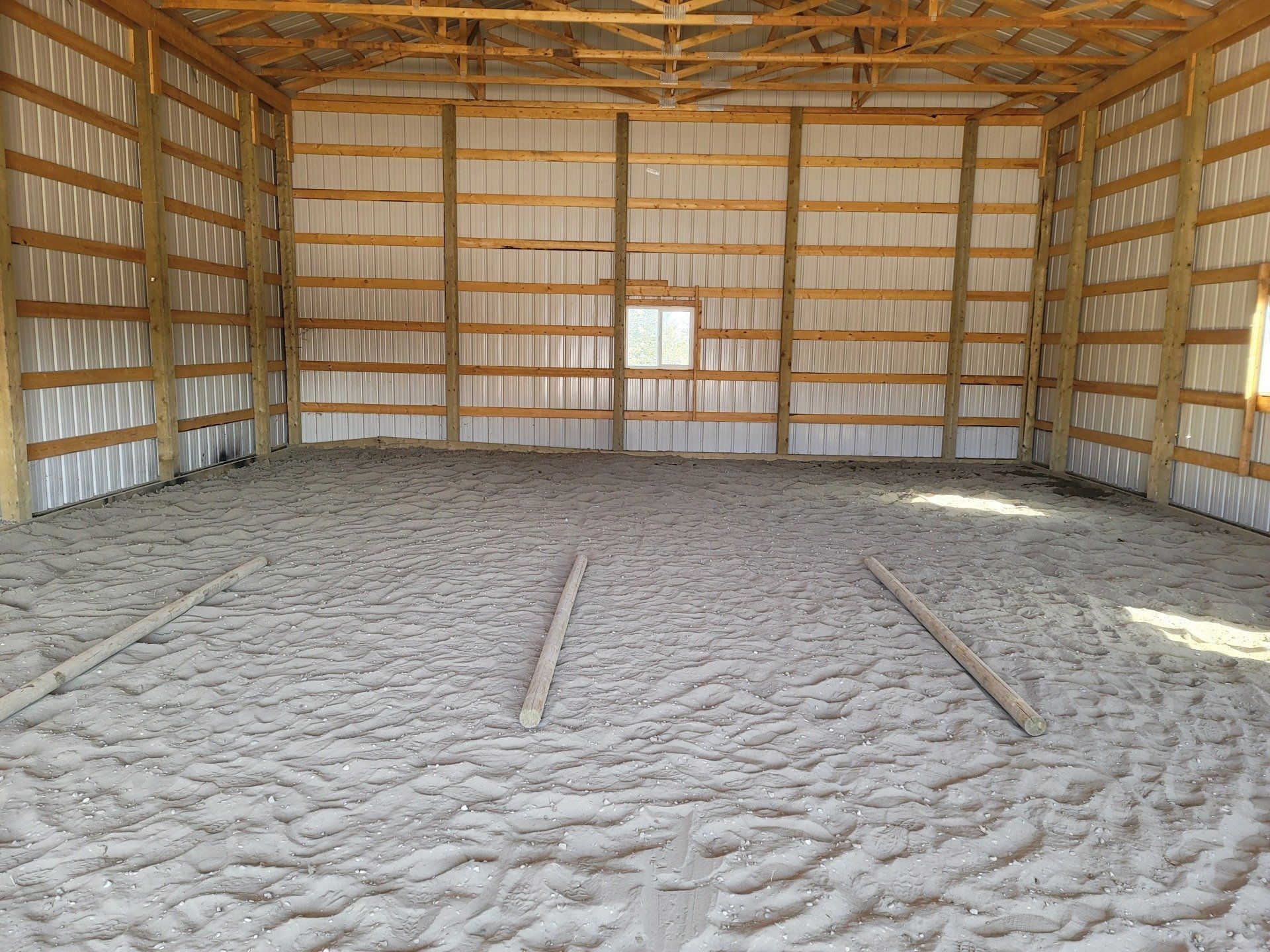 A large empty barn with a concrete floor and wooden walls.