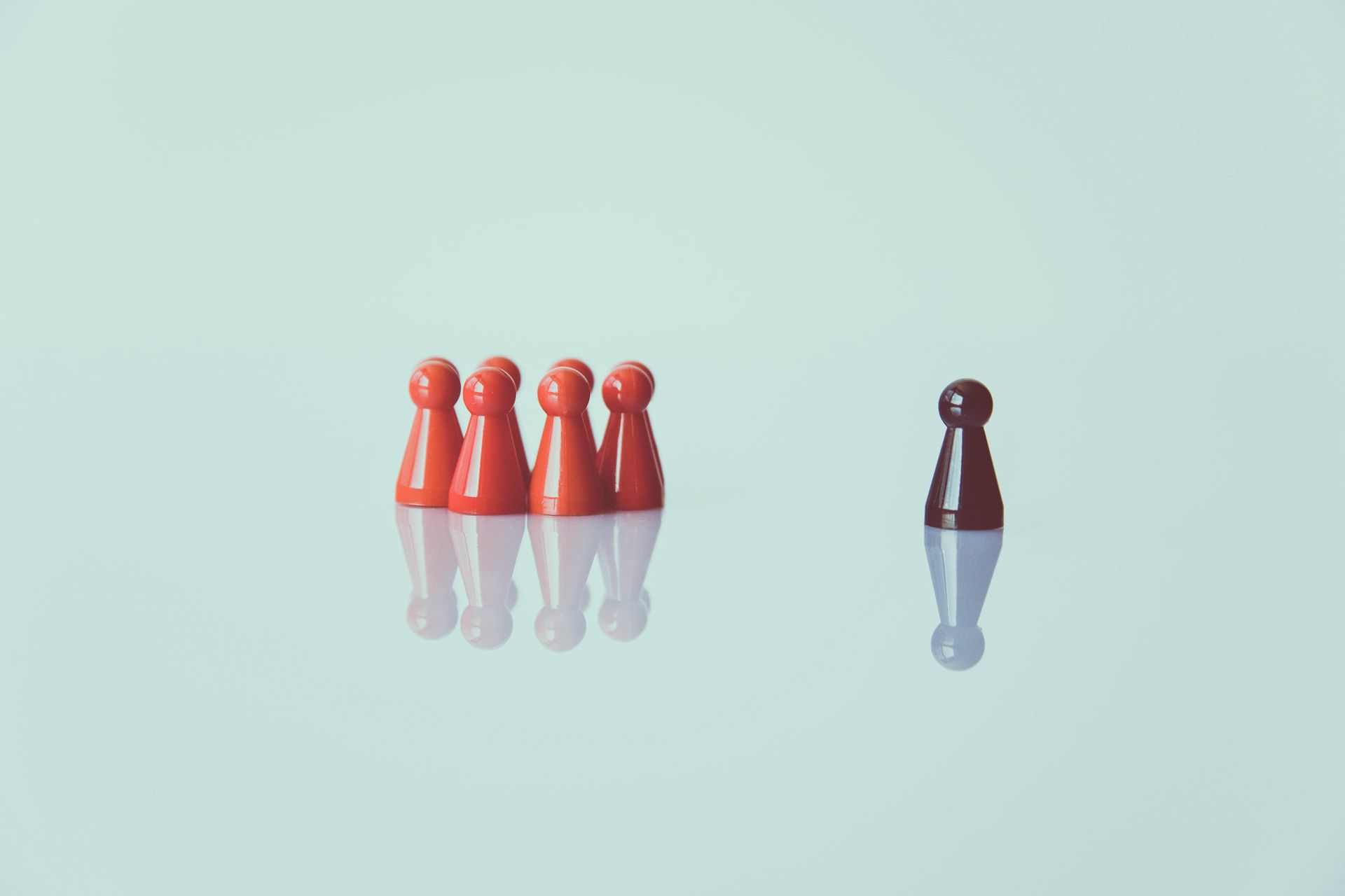 A group of red chess pieces and a black chess piece on a table.