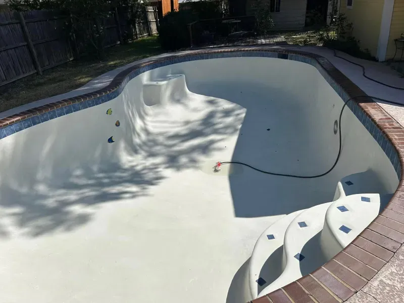 An empty swimming pool with stairs and a hose coming out of it.