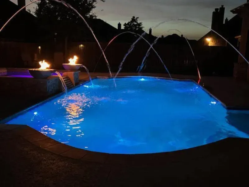 A large swimming pool is lit up at night