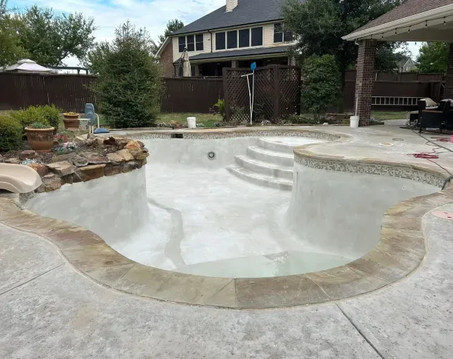 A large swimming pool is being built in the backyard of a house.