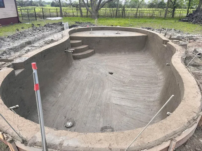 A large swimming pool is being built in a backyard.