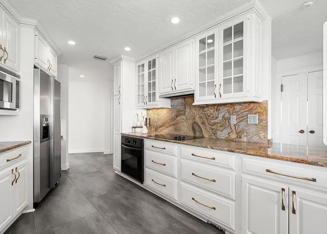 Spacious kitchen with wooden cabinets, an island, and stainless steel refrigerator on tile floor. Spacious kitchen with wooden cabinets, an island, and stainless steel refrigerator on tile floor.