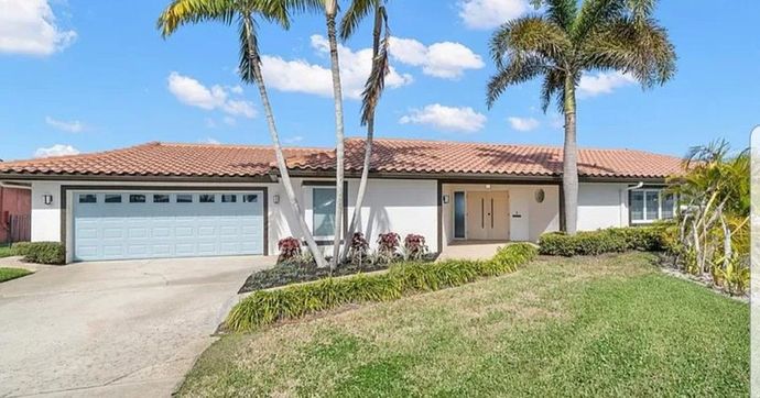 Ranch-style house with a terracotta roof, blue garage door, and palm trees on a sunny day. Ranch-style house with a terracotta roof, blue garage door, and palm trees on a sunny day.