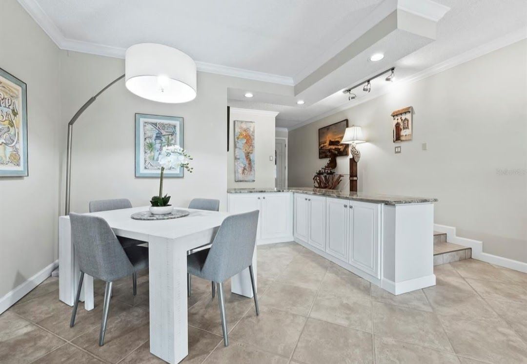 Dining room with white table, gray chairs, and overhead lighting.