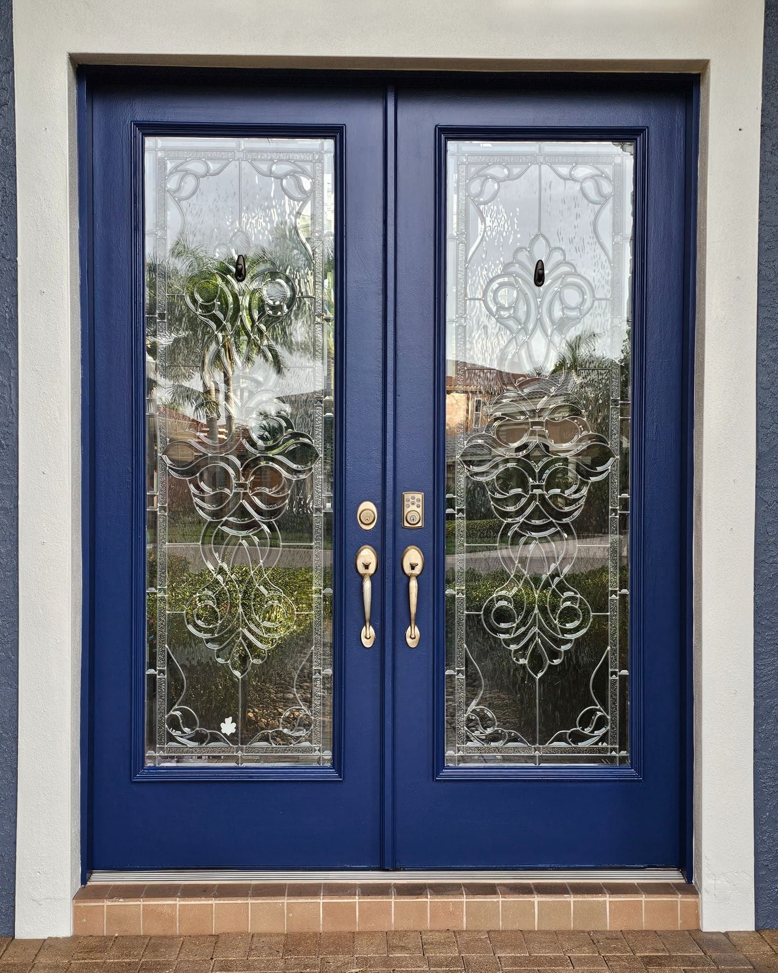 Blue double doors with decorative glass panes and brass hardware. Blue double doors with decorative glass panes and brass hardware.