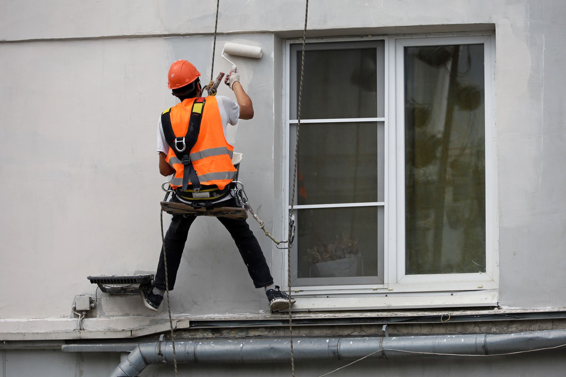 A man is painting the exterior of a building.