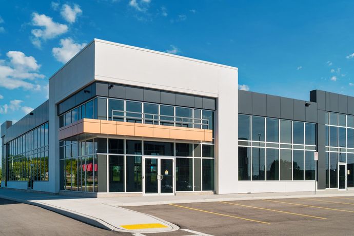 Modern commercial building with glass windows and gray and white exterior; blue sky. Modern commercial building with glass windows and gray and white exterior; blue sky.