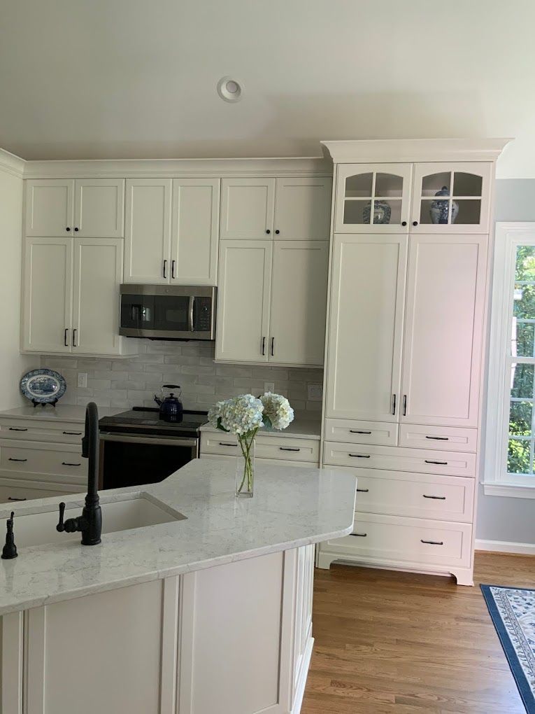 A kitchen with white cabinets and a vase of flowers on the counter