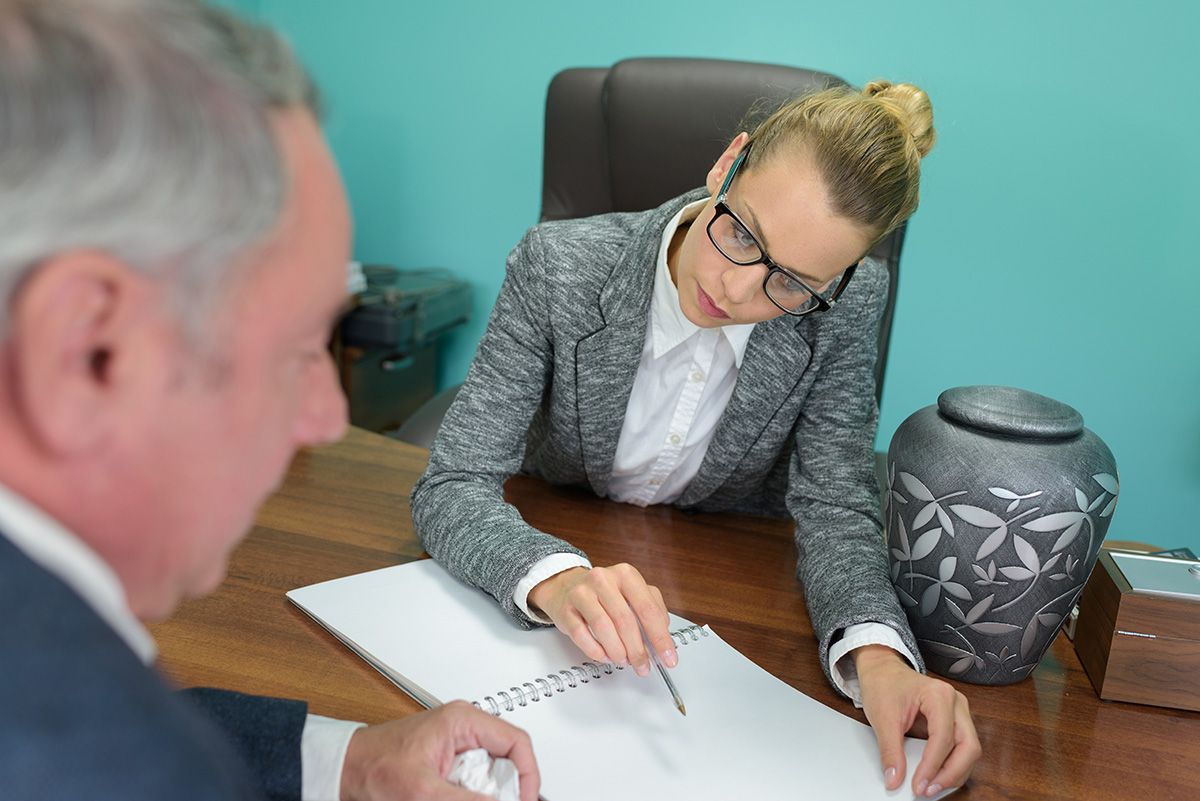 A woman is sitting at a desk talking to a man.