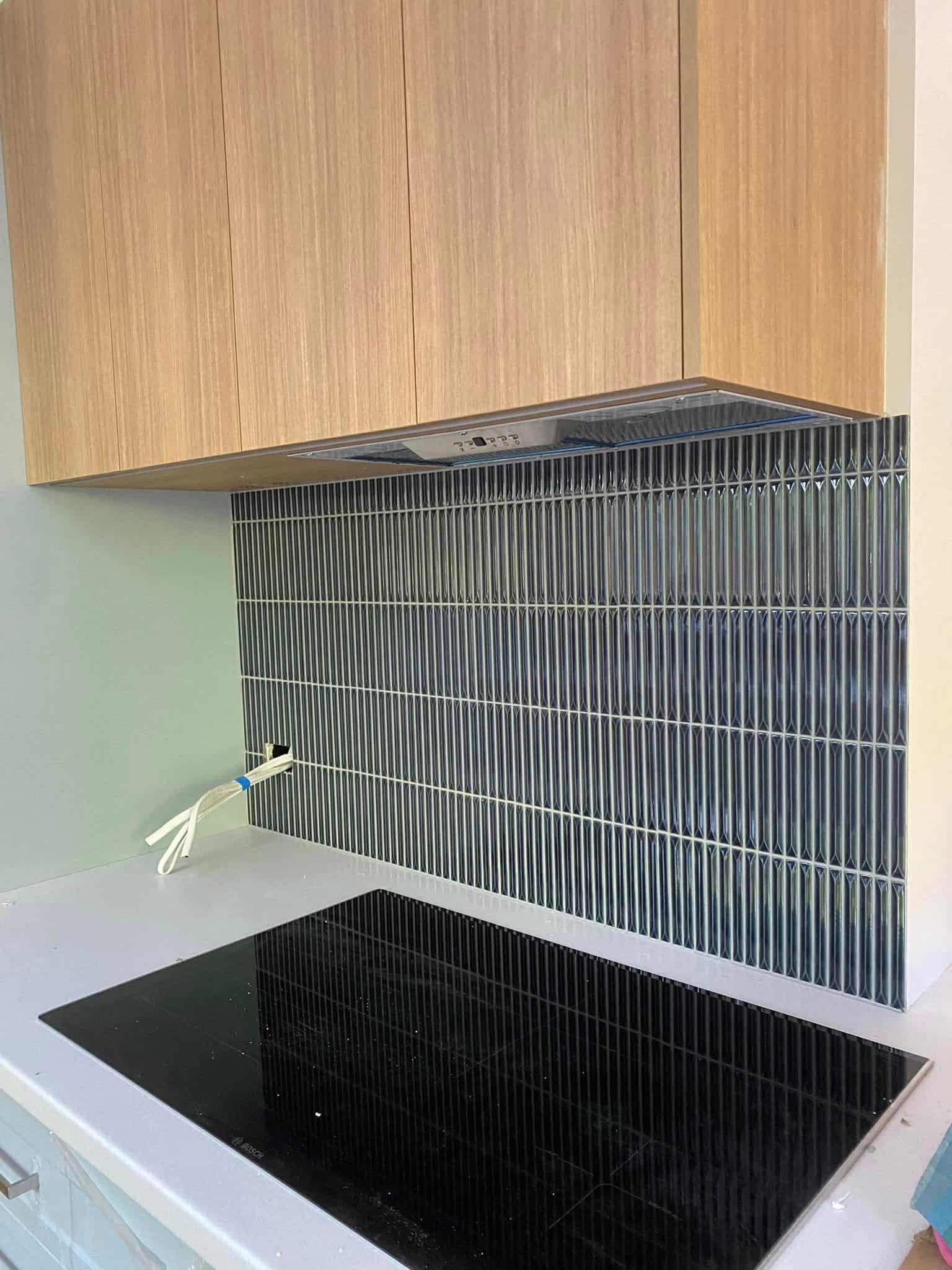 A Kitchen Stovetop With a Modern Gray Vertical-tile — Rectified Edge Tiling & Bathroom Renovations in Jamison Centre, ACT