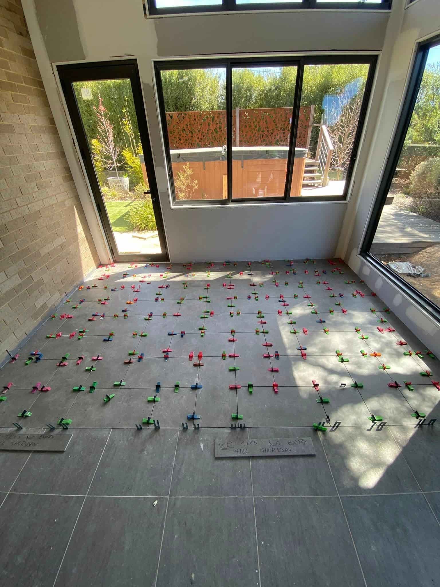 A Sunroom Floor in Progress With Large Grey Tiles — Rectified Edge Tiling & Bathroom Renovations in Jamison Centre, ACT