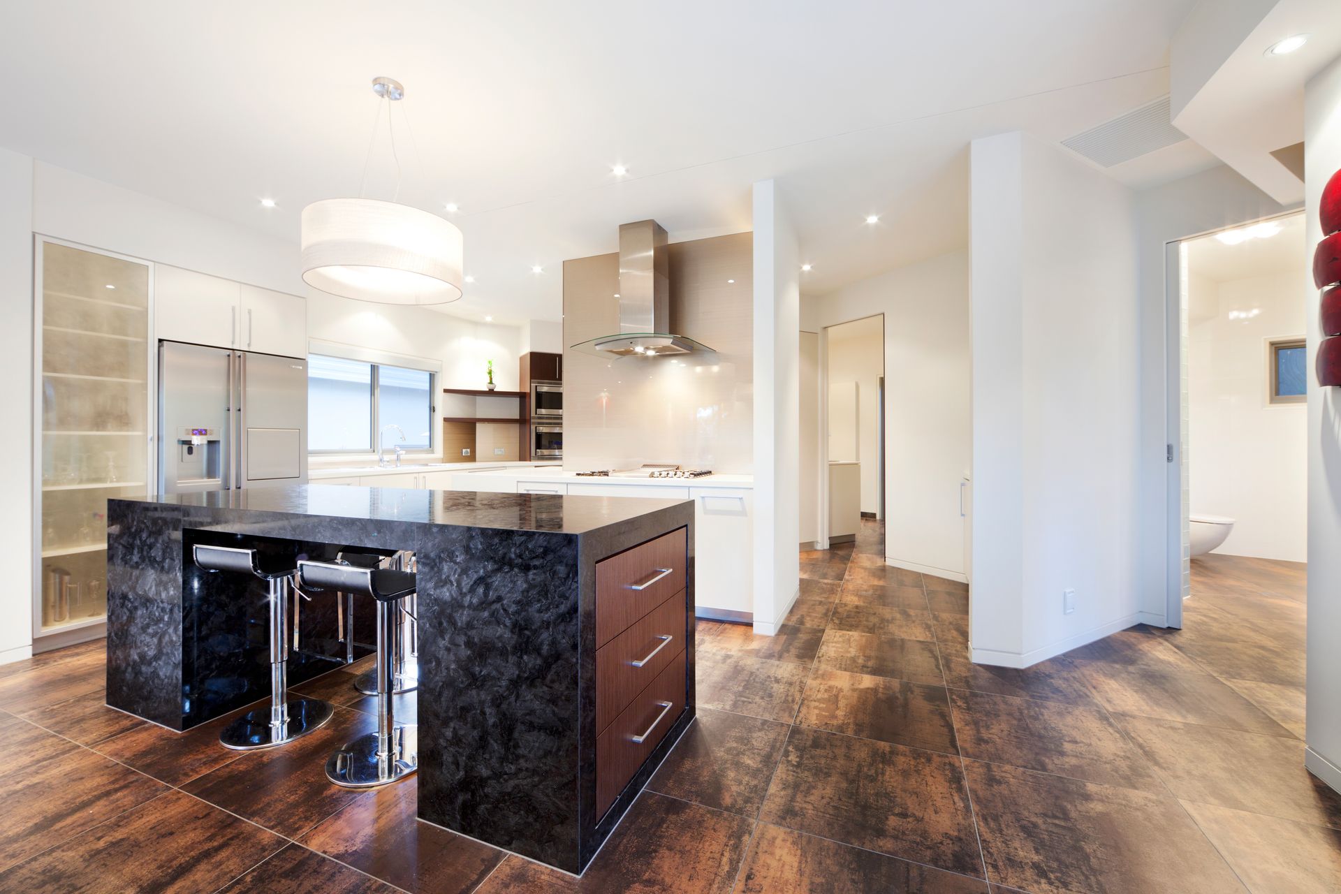Modern kitchen with dark granite island, stainless steel appliances, and wood flooring. — Rectified Edge Tiling & Bathroom Renovations in Fyshwick, ACT