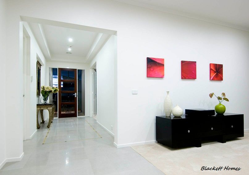 Interior hallway with white walls, black cabinet, and three red paintings. — Rectified Edge Tiling & Bathroom Renovations in Yass, NSW