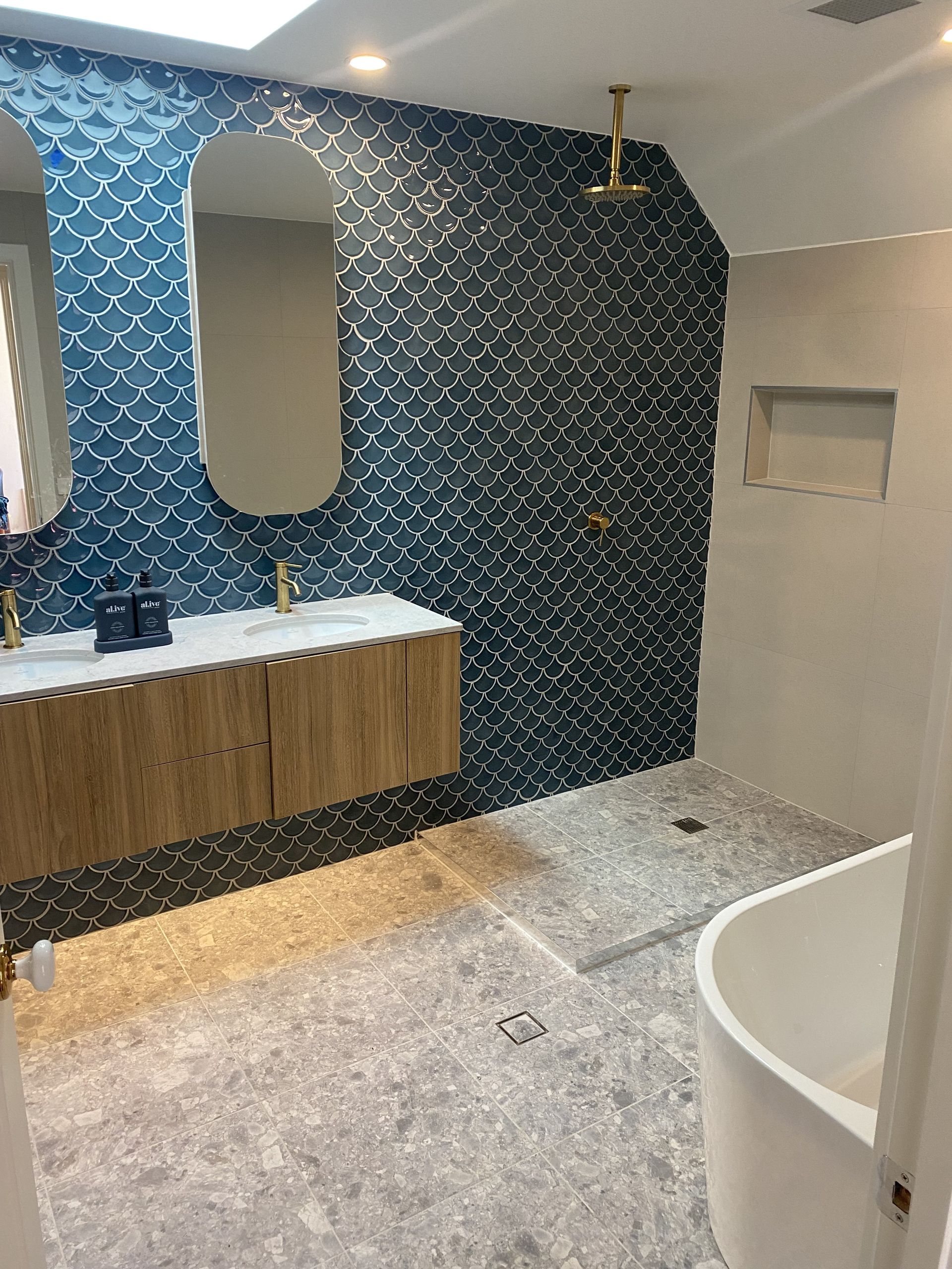 Modern bathroom with blue tile accent wall, wood vanity, and soaking tub. — Rectified Edge Tiling & Bathroom Renovations in Batemans Bay, NSW