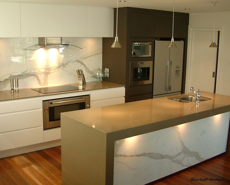 Modern kitchen with light countertops, white cabinetry, and a dark brown accent wall. — Rectified Edge Tiling & Bathroom Renovations in Batemans Bay, NSW