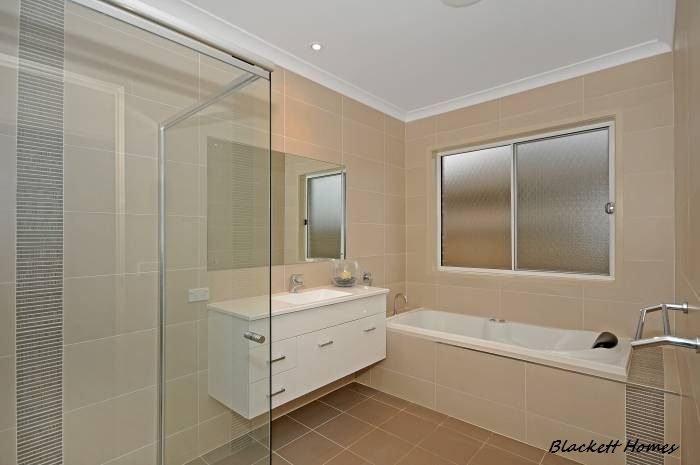 Bathroom with beige tiles, shower, vanity, bathtub, and frosted window. — Rectified Edge Tiling & Bathroom Renovations in Batemans Bay, NSW