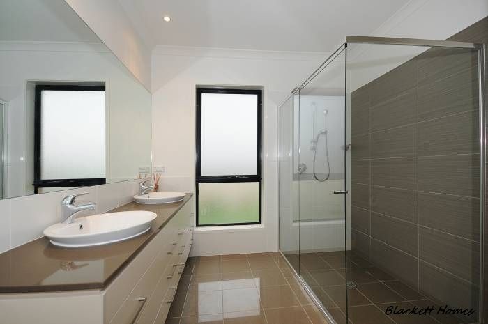 Modern bathroom with long vanity, two sinks, and glass shower. — Rectified Edge Tiling & Bathroom Renovations in Batemans Bay, NSW