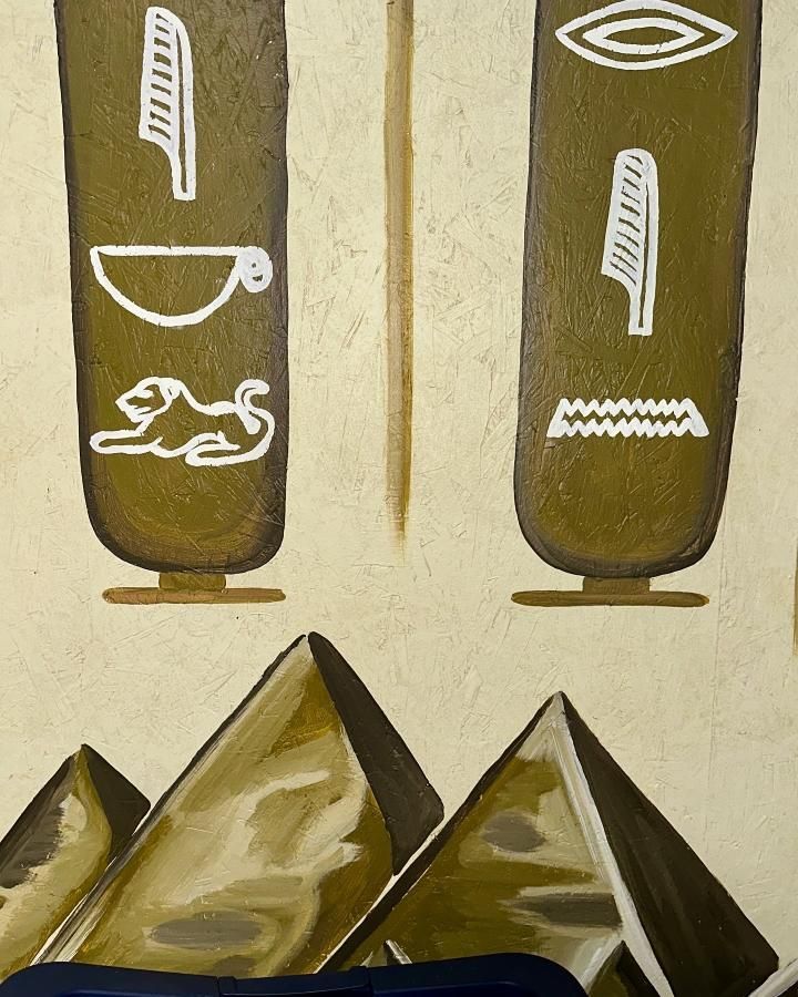 Ancient Egyptian scene with pyramids and hieroglyphs in olive and white.