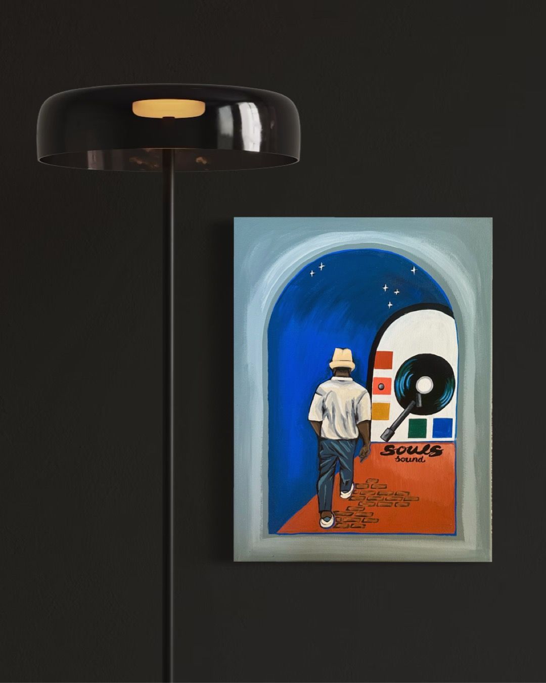 A man walking towards an archway with a record, painting, and floor lamp on a dark wall.