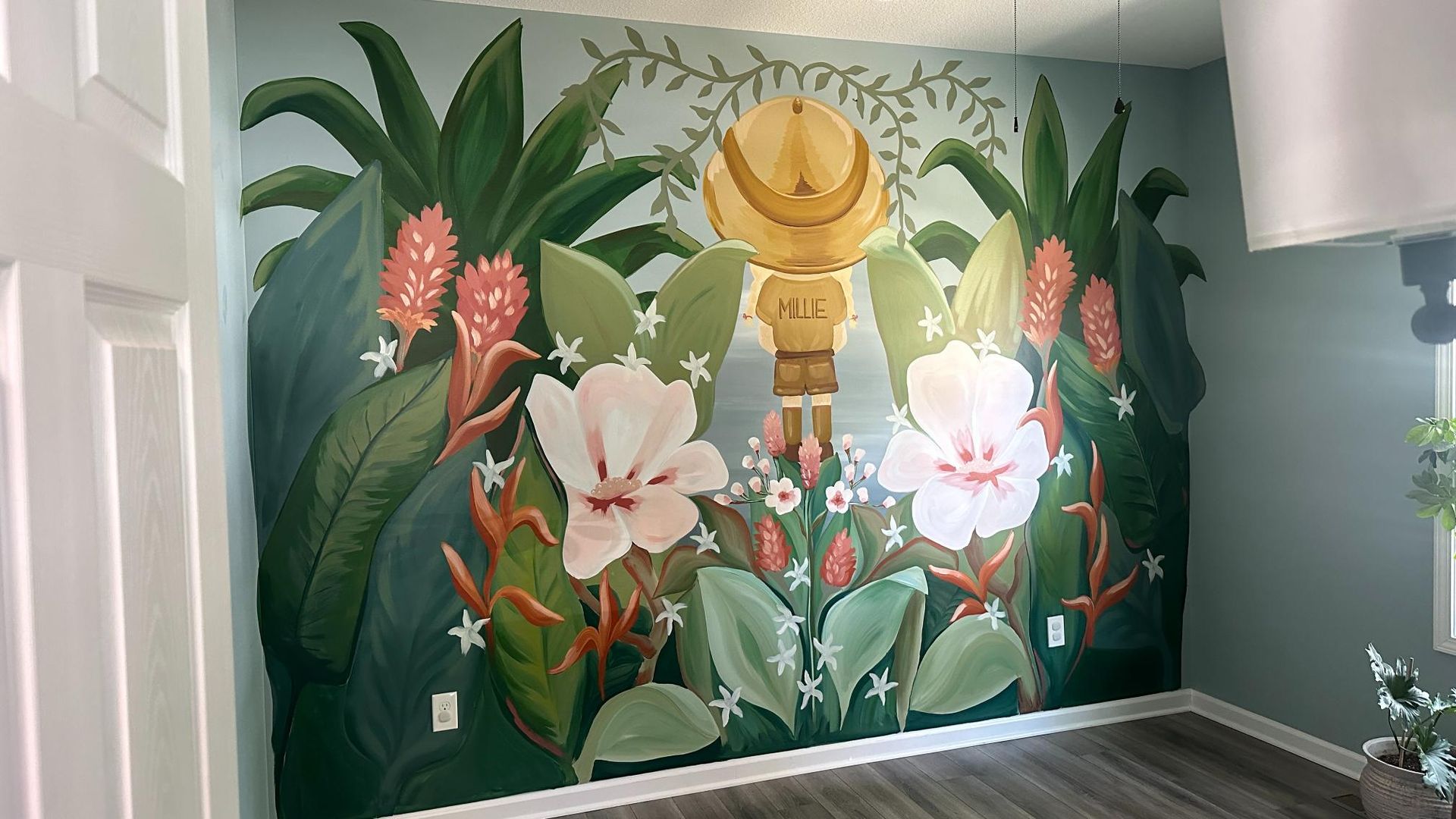 Colorful floral mural on a wall, featuring large leaves, flowers, and a central gold form.