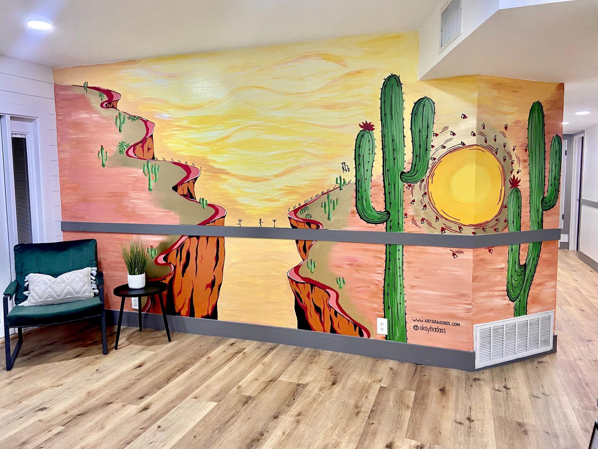 Southwest desert mural with cacti and setting sun on a wooden wall, alongside a chair.