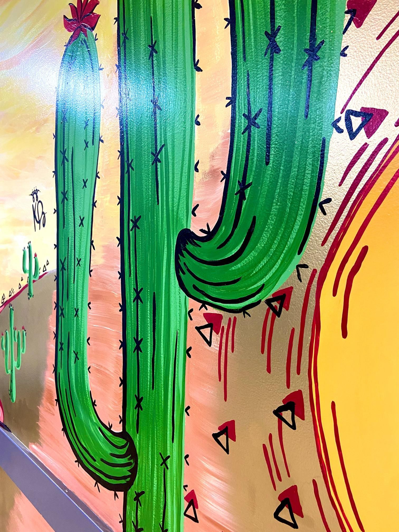 Green cactus mural with red triangles and a yellow sun.