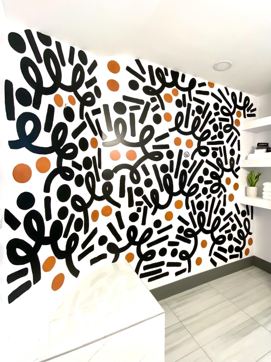 Abstract mural in black, copper, and white on a wall.