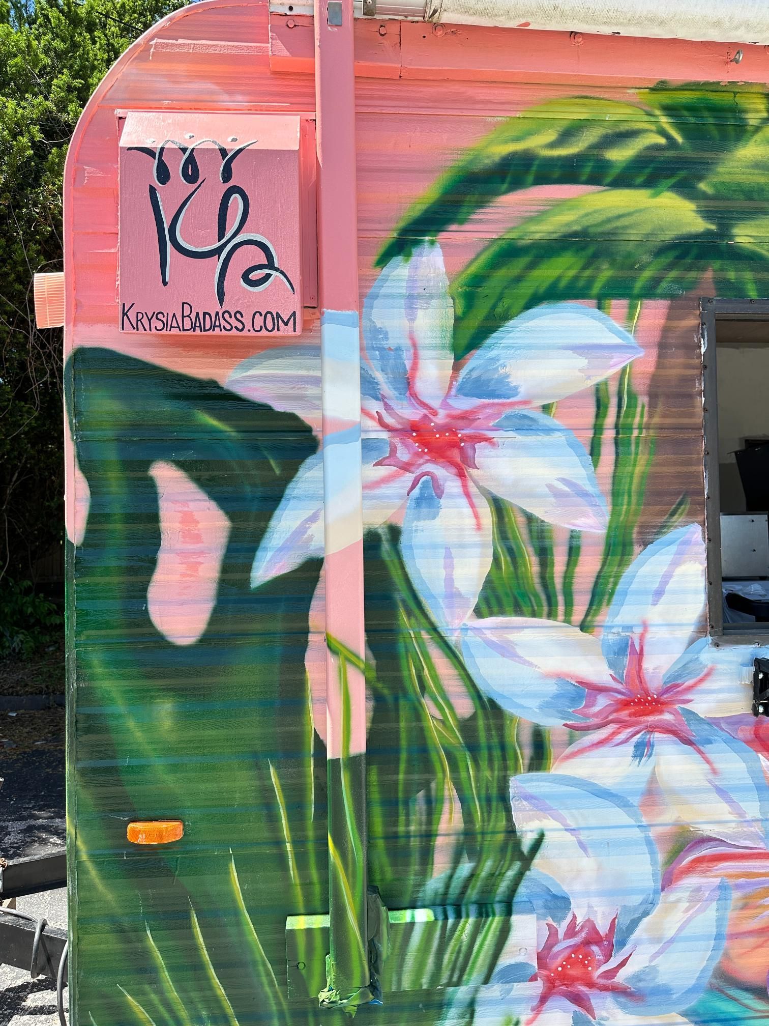 Pink and green mural with white and pink flowers on a building.