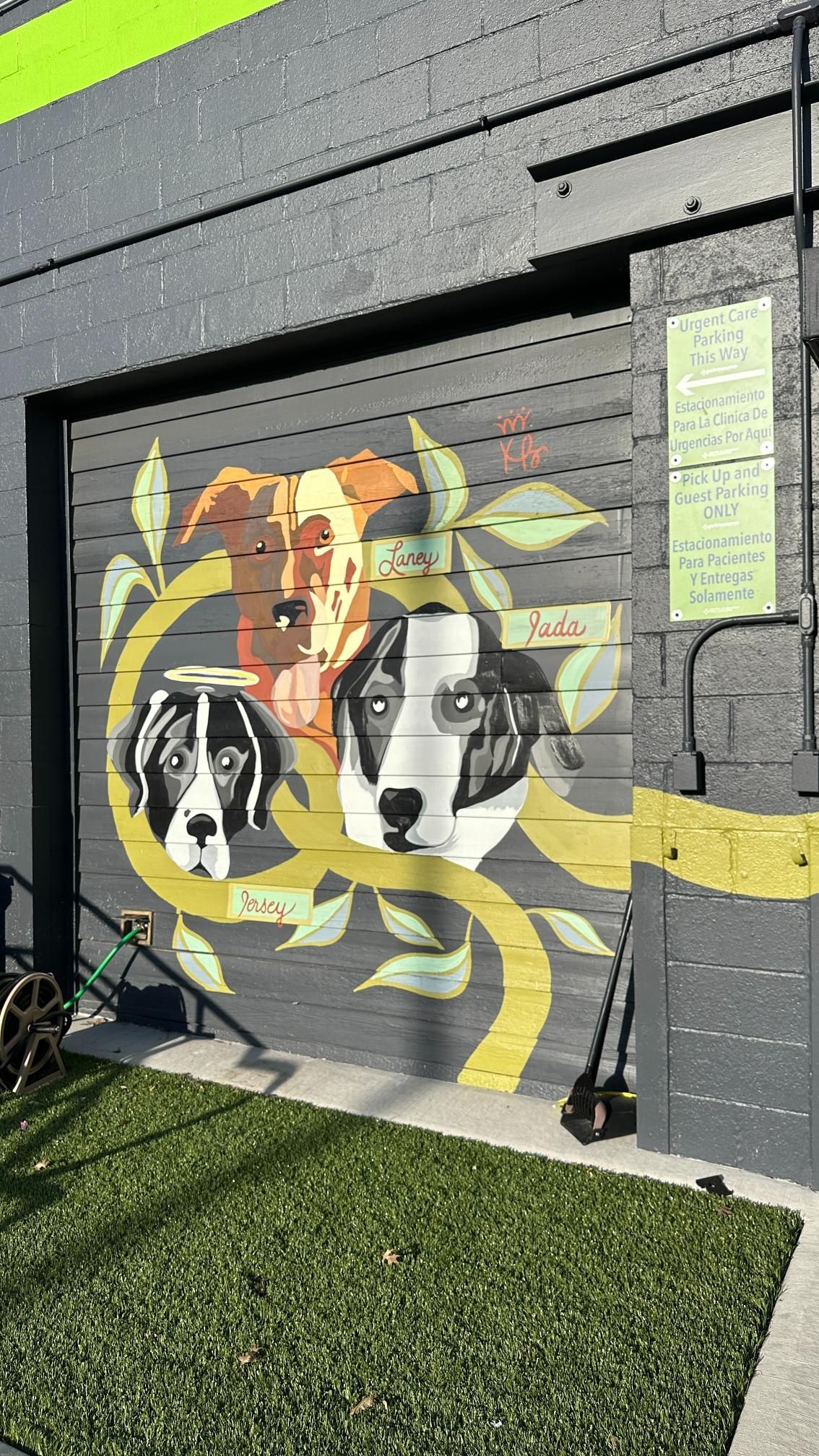 Mural of three dogs with leaves, on a gray garage door.
