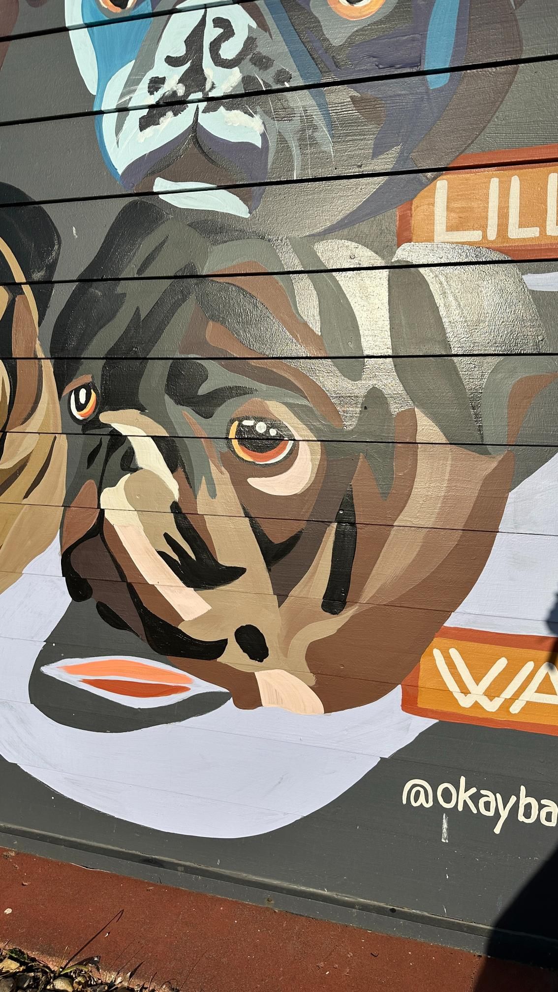 Mural of a pug dog with soulful brown eyes and a dark, wrinkly face. The dog has a brown and tan coat.