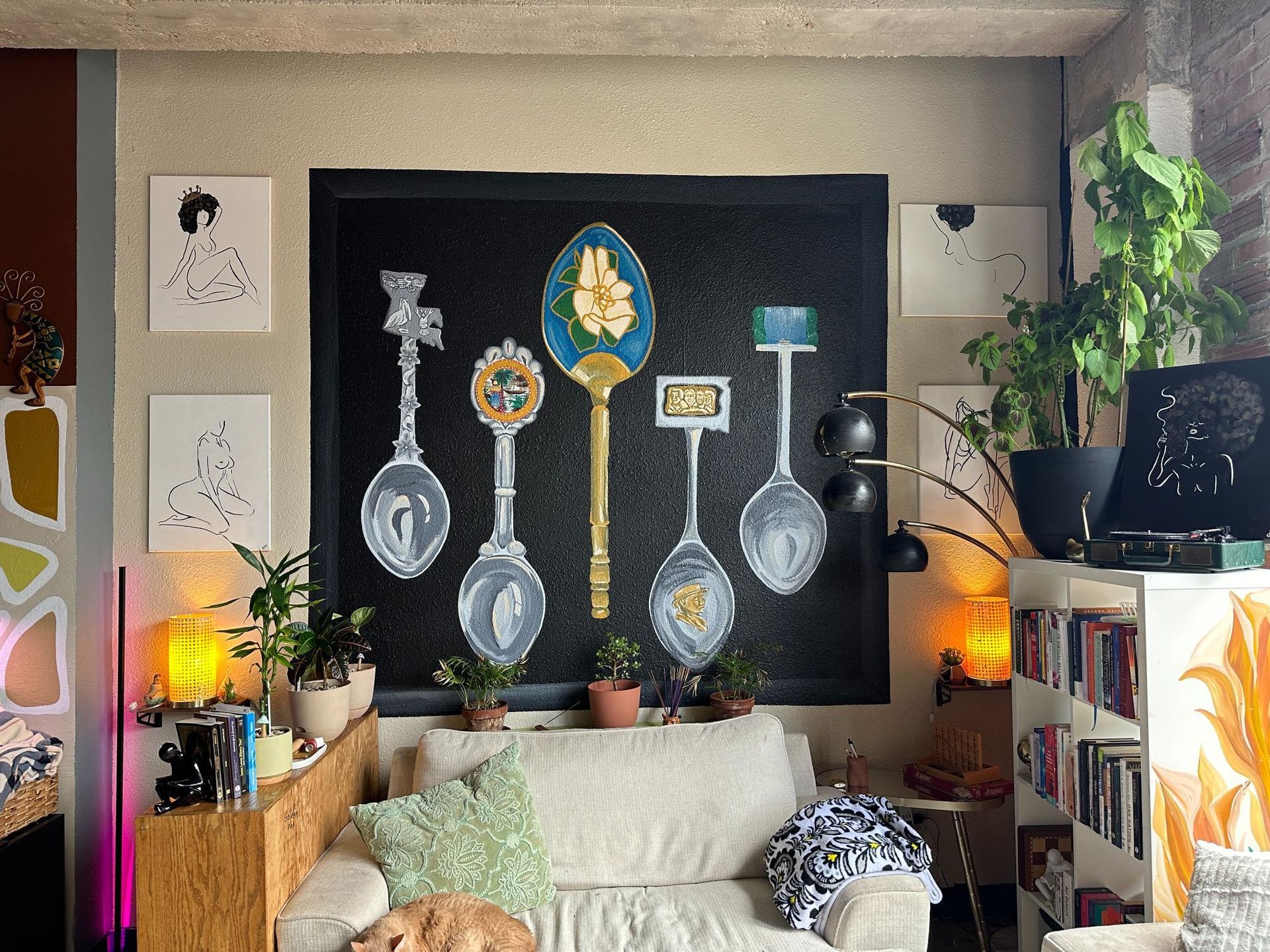 Living room with spoon art, plants, couch, and books.