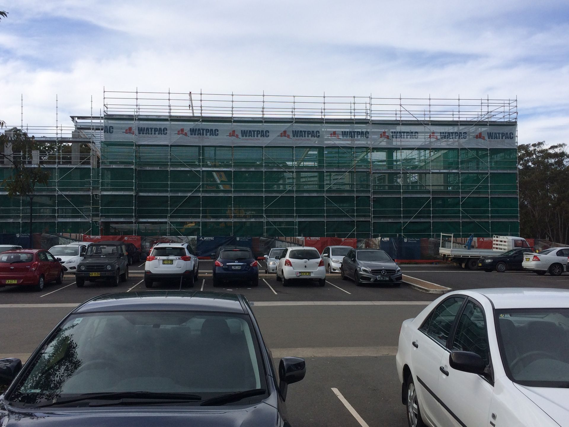 A carpark with a building being built and cars parked— Commercial Painting Group in Kembla Grange, NSW
