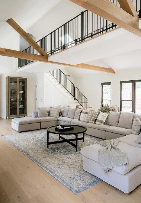 The inside of a house with a large grey couch, a carpet, small black table and stairs leading up — Commercial Painting Group in Kembla Grange, NSW