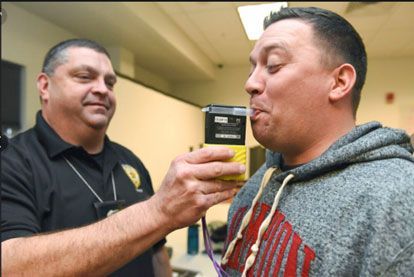 A man is being tested for alcohol by a police officer.