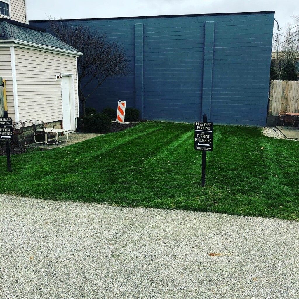 Lush green lawn with fresh mower stripes, next to a building and a blue wall.