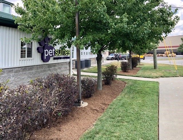 Exterior of Pet Suites building with trees and landscaping.