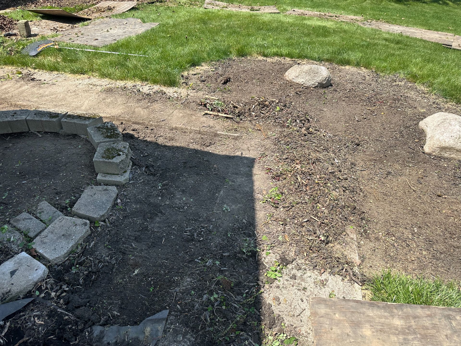 Dirt and stone fire pit in a yard with patchy grass.