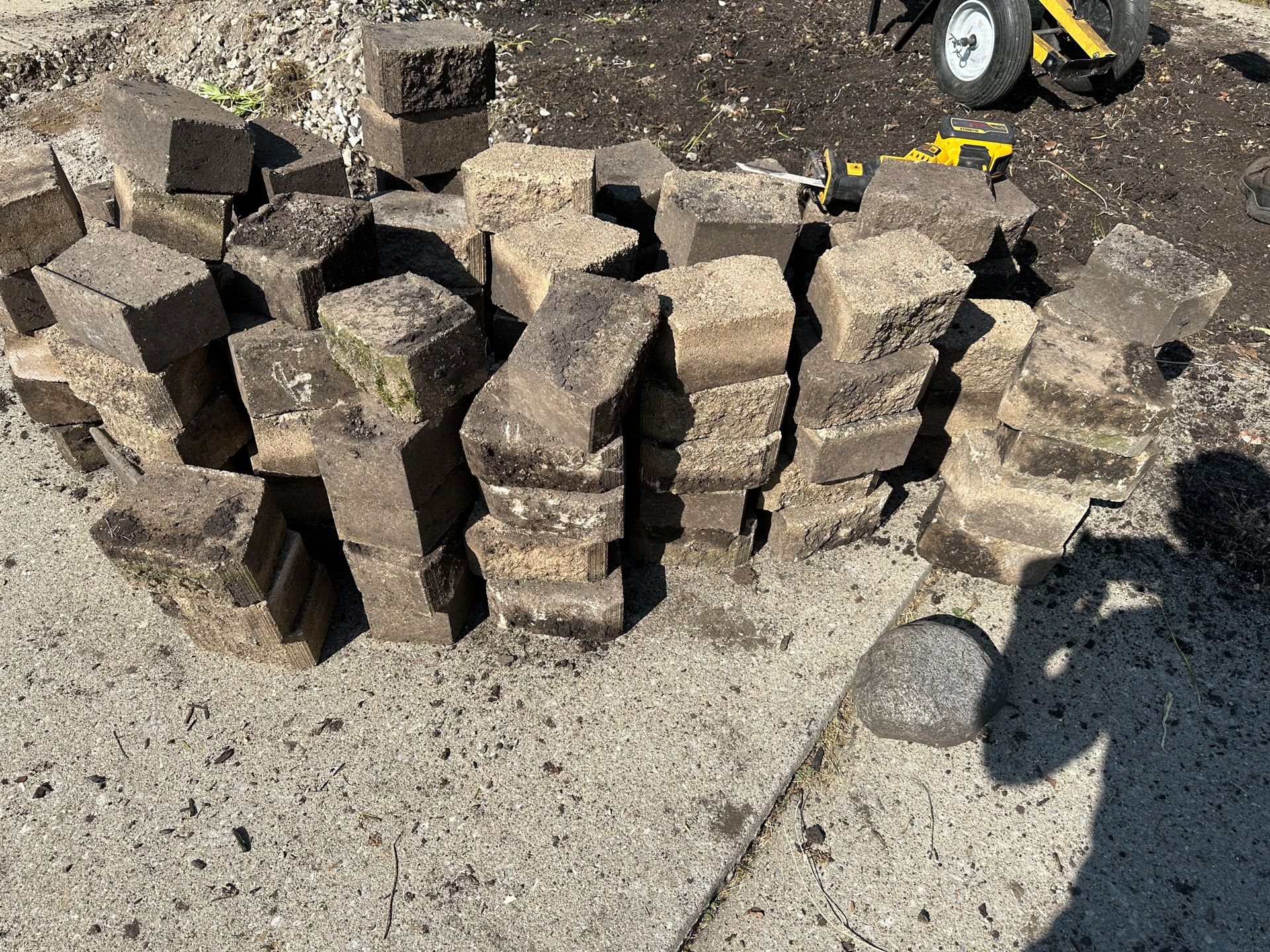 Pile of dark brown, weathered bricks on concrete.
