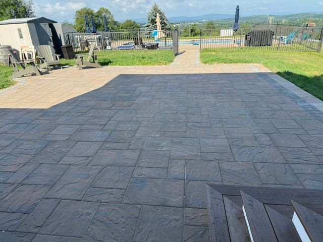 A patio with a shed and a pool in the background