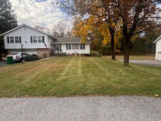 House with white siding and brick, lawn with autumn colors, driveway.