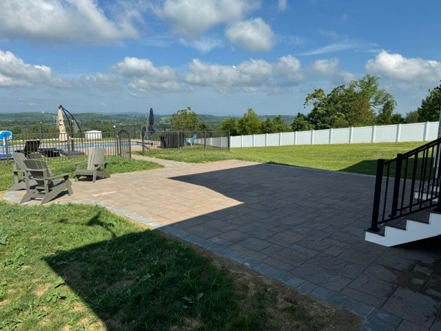 A backyard with a patio and stairs leading to a pool.
