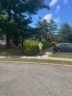 A man in a yellow jacket is standing on the sidewalk in front of a house.
