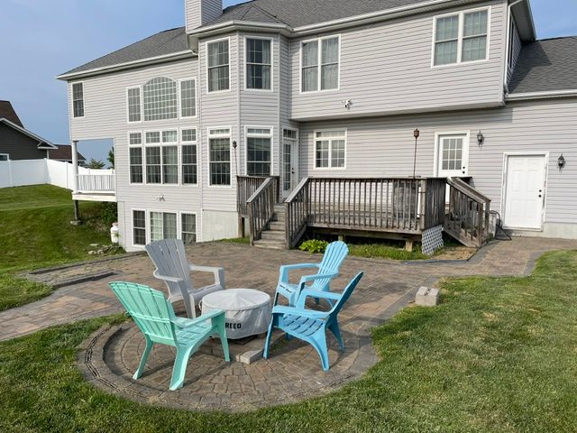 A patio with chairs and a table in front of a large house.