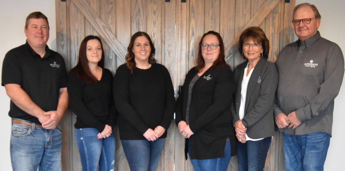 Group of people posing in front of a wooden wall. They are wearing casual clothes.