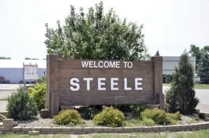 An aerial view of a highway intersection at night with a city in the background.