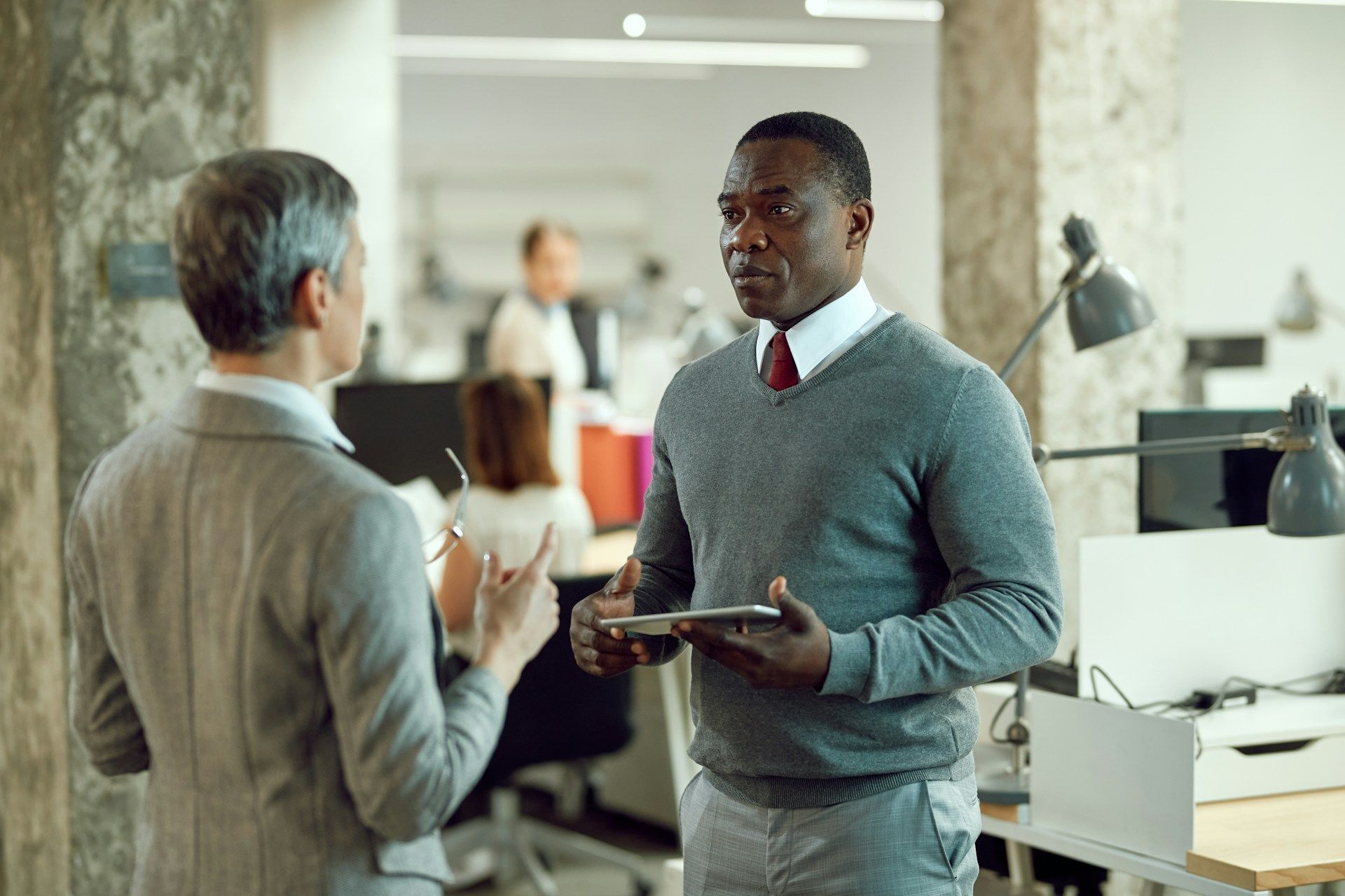 Two young boys are laying on the grass and talking to each other.