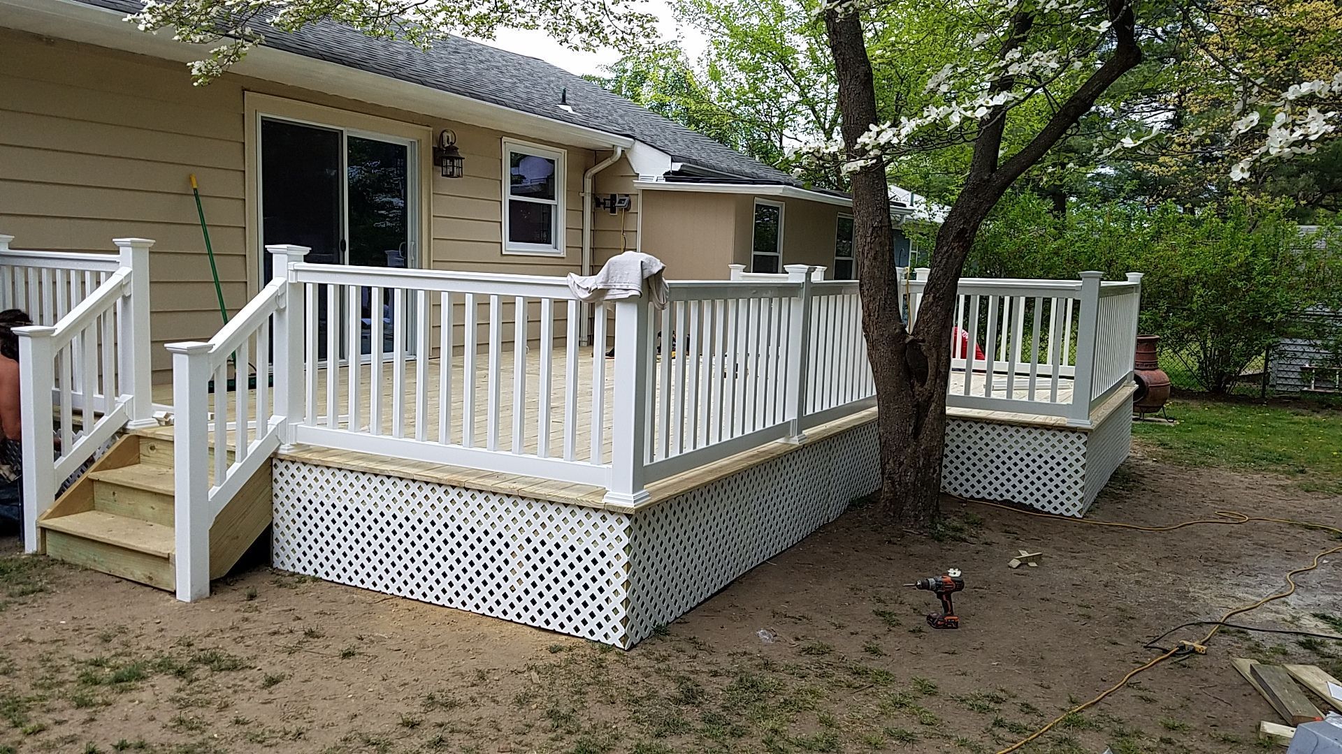 A white deck with stairs is in front of a house.