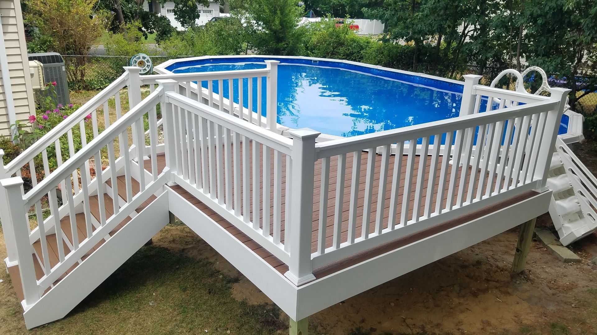 A swimming pool on a deck with stairs leading to it.